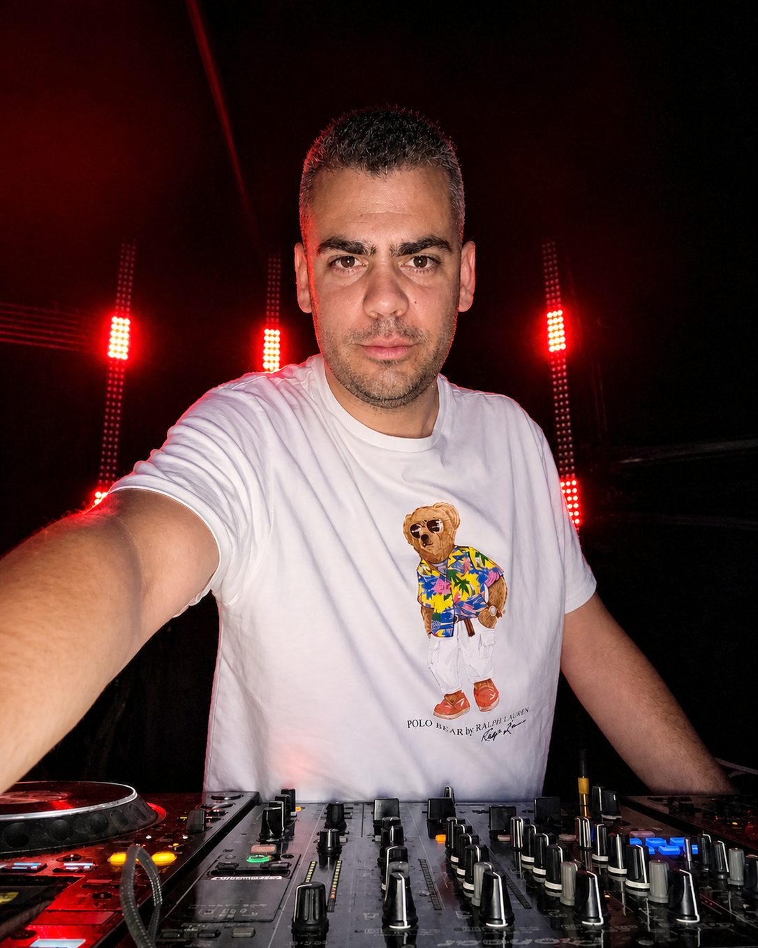 DJ Orestis at a Pioneer mixer under red stage lighting