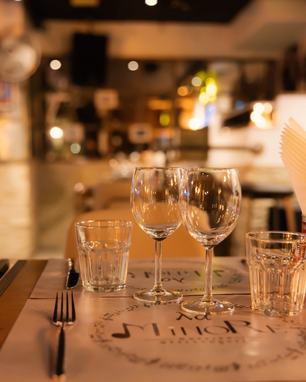 A laid restaurant table with wine glasses and warm lighting before service